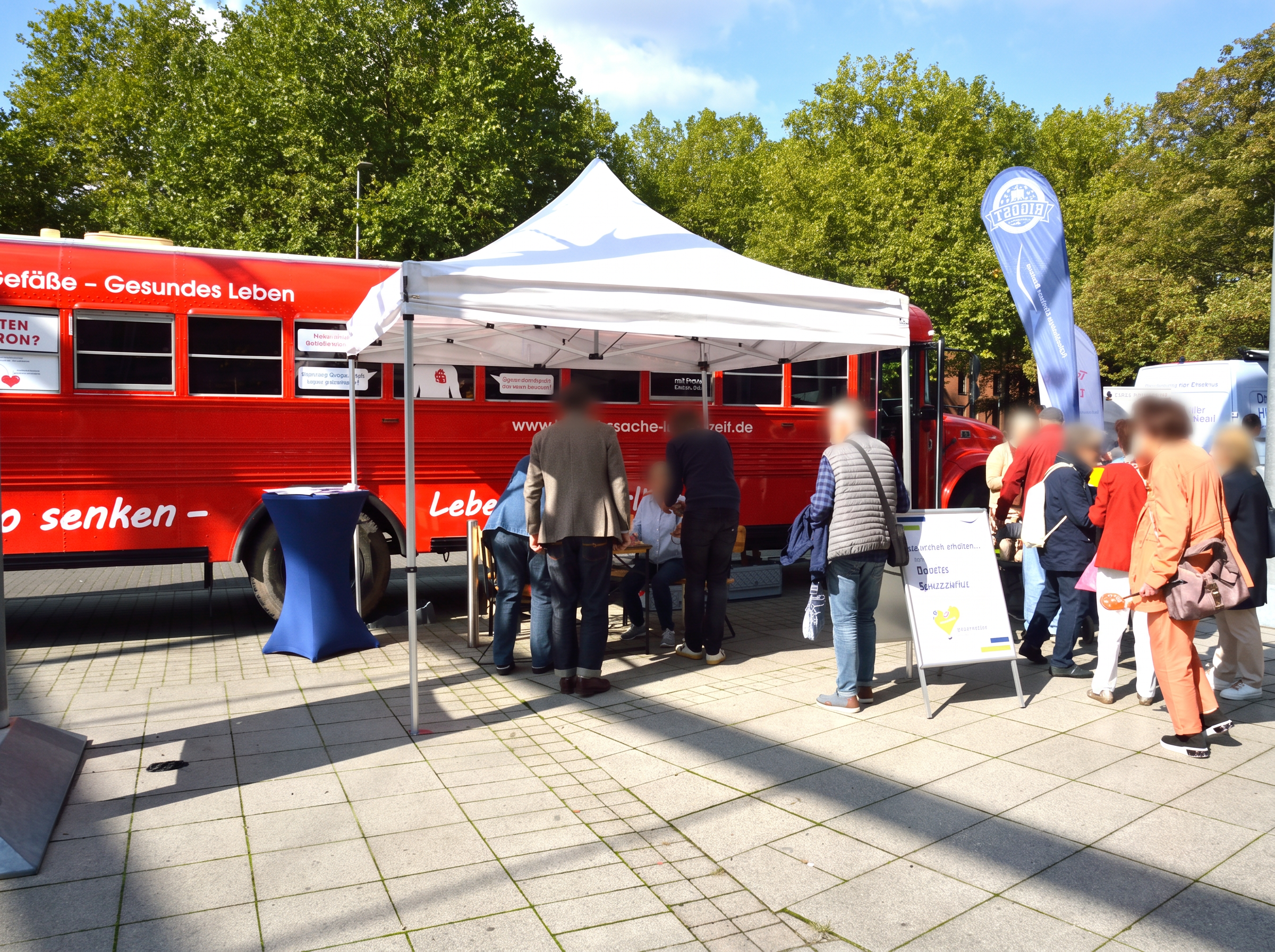 Außenbereich der Gesundheitsmesse Bochum mit Infomobil, Pavillon und Besucherinnen und Besuchern